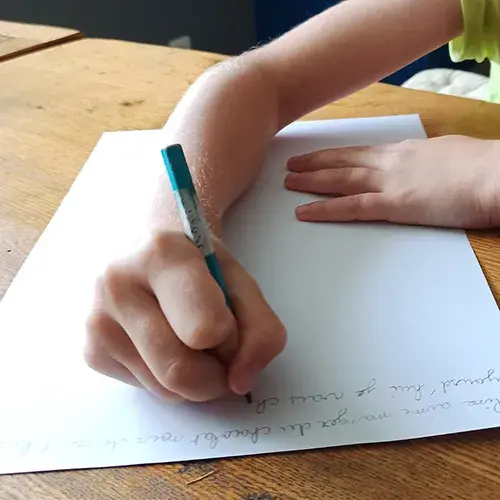 Enfant en séance de graphopédagogie travaillant son écriture manuscrite.